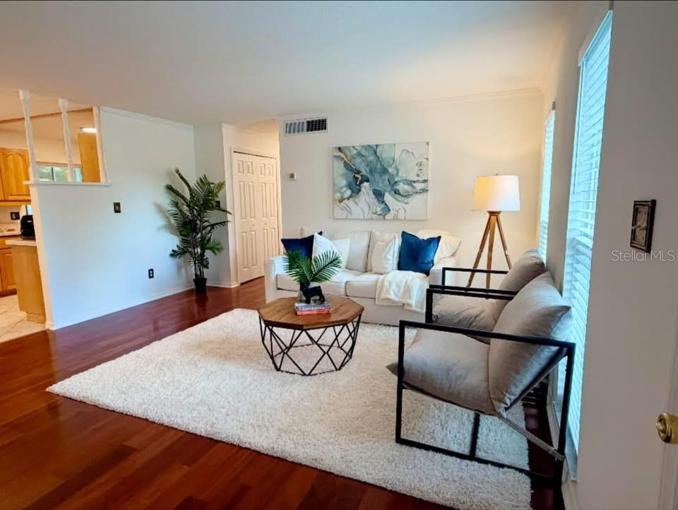 A living room with hardwood floors, a white rug, a sofa, and two armchairs — 7514 LAUREL SPRINGS DRIVE, WINTER PARK, FL
