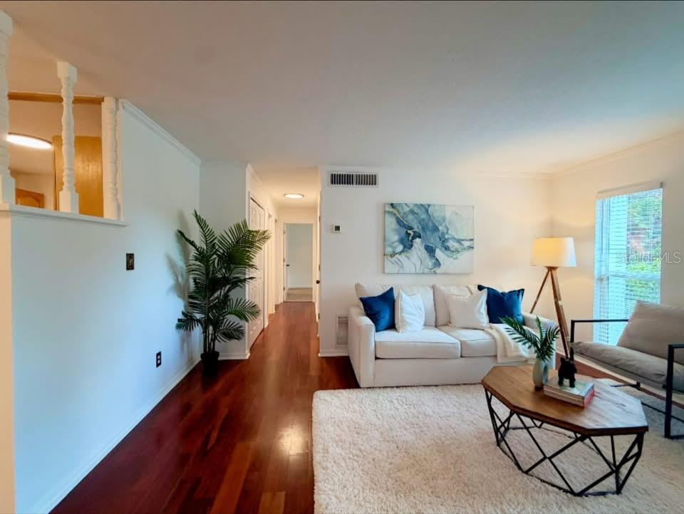 A living room with hardwood floors, a white sofa, a coffee table, and a hallway — 7514 LAUREL SPRINGS DRIVE, WINTER PARK, FL