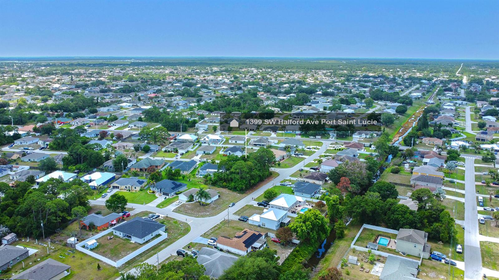 An aerial view shows a residential neighborhood with single-family homes and surrounding green space — 1399 SW Halford Avenue, FL 34953, FL