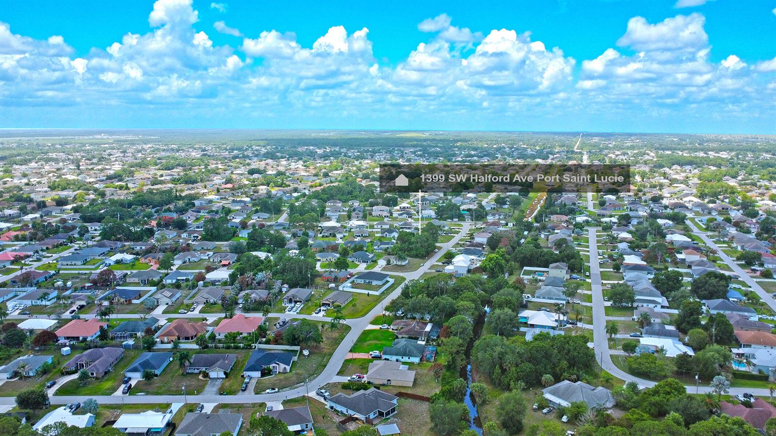 An aerial view shows a residential neighborhood with single-family homes and a small canal — 1399 SW Halford Avenue, FL 34953, FL