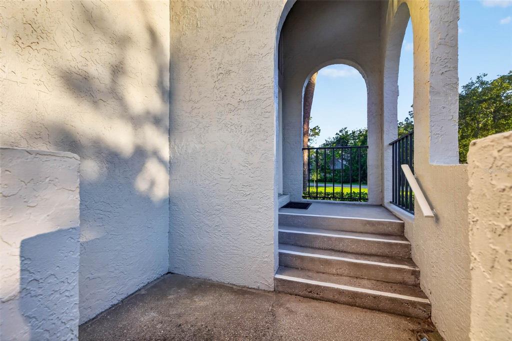 An outdoor entryway features concrete stairs leading to an arched porch with a black railing — 4843 NAPOLI COURT NE, ST PETERSBURG, FL