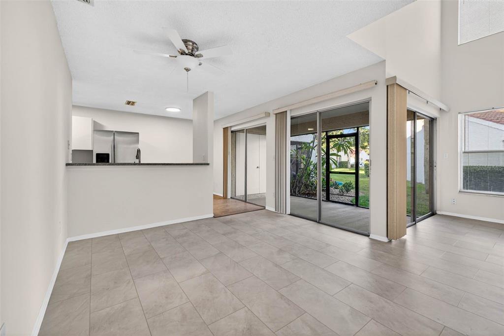 A living room with light tile flooring, a ceiling fan, and sliding glass doors to a patio — 4843 NAPOLI COURT NE, ST PETERSBURG, FL