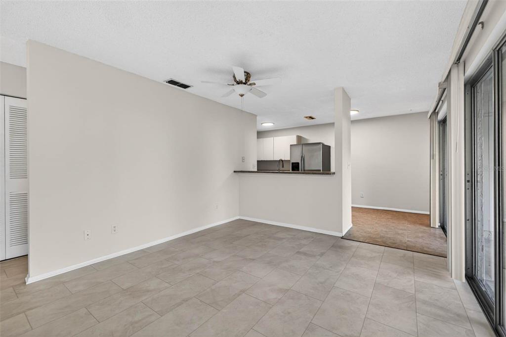 An open-concept dining area with tile flooring leads to a kitchen with a breakfast bar — 4843 NAPOLI COURT NE, ST PETERSBURG, FL