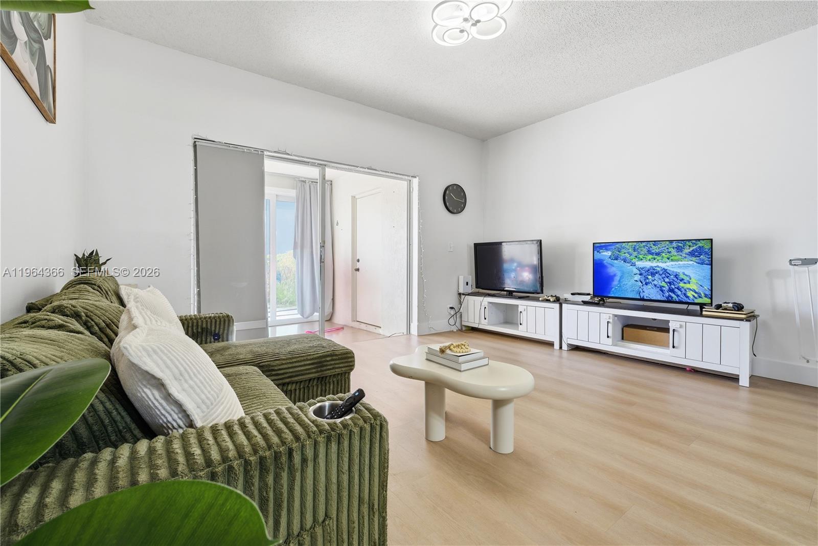 A living room features a green corduroy sectional, a coffee table, and two white media consoles — 2 Simonton Cir, Weston FL 33326, WESTON, FL