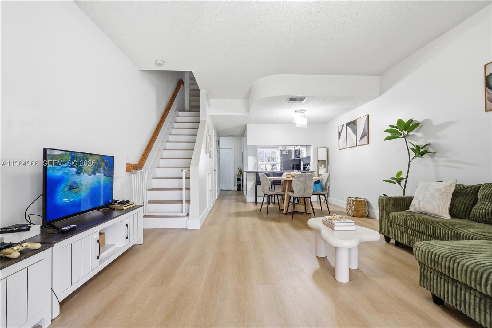 A living room and dining area feature light wood flooring, white walls, and stairs — 2 Simonton Cir, Weston FL 33326, WESTON, FL