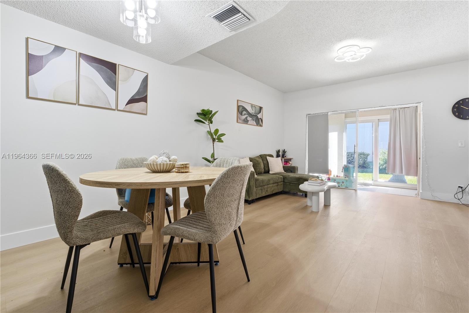A dining area with a round wooden table sits adjacent to a living room space — 2 Simonton Cir, Weston FL 33326, WESTON, FL