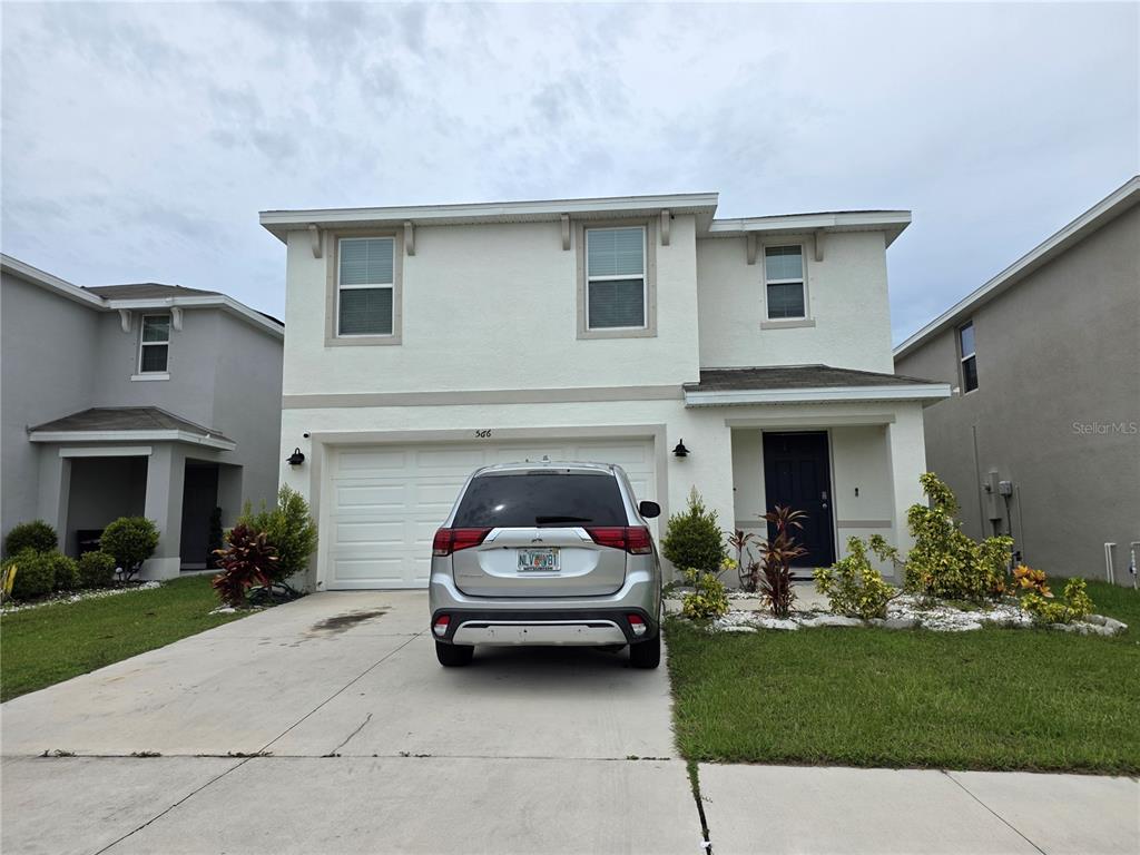 A two-story house with a white stucco exterior and a silver SUV parked in front — 566 SUNLIT CORAL STREET, RUSKIN, FL