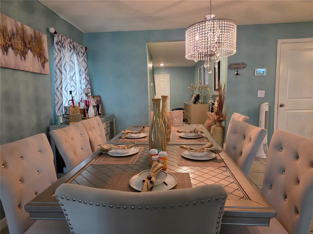 A dining room features a crystal chandelier, a silver table, and tufted upholstered chairs — 566 SUNLIT CORAL STREET, RUSKIN, FL