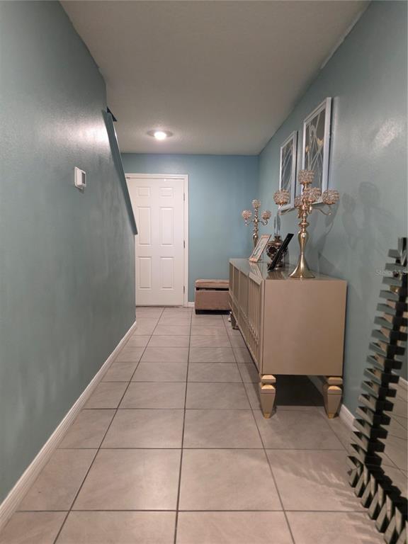 A hallway features light blue walls, tiled flooring, a beige sideboard, and a white door — 566 SUNLIT CORAL STREET, RUSKIN, FL
