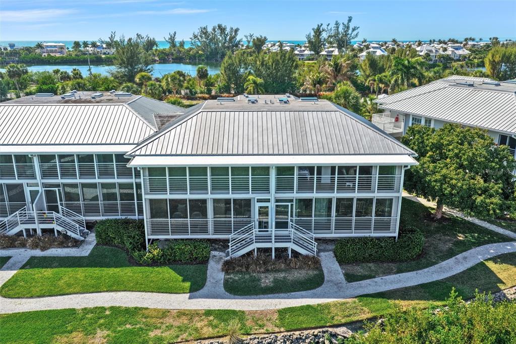 An elevated exterior view of a multi-story building with a metal roof and screened balconies — 5854 GASPARILLA ROAD UNIT M22, BOCA GRANDE, FL