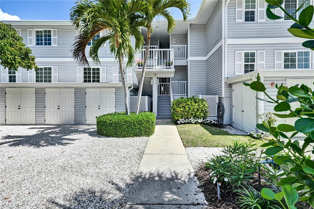 A multi-story residential building with light gray siding, a palm tree, and a concrete walkway — 5854 GASPARILLA ROAD UNIT M22, BOCA GRANDE, FL