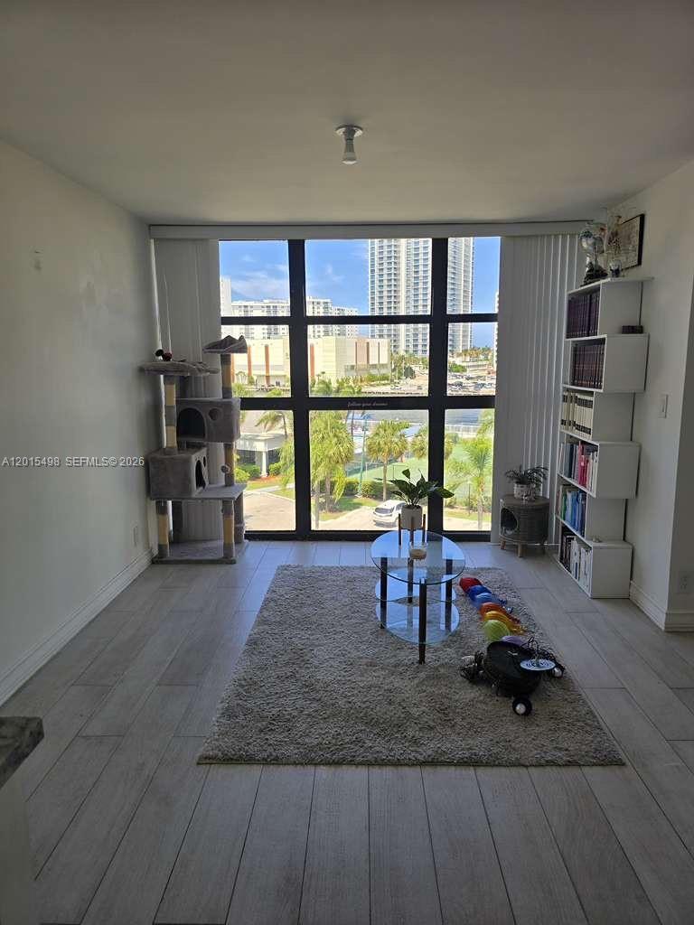 A living room features light wood-look flooring, a glass coffee table, and floor-to-ceiling windows — 400 Leslie Dr # 508, Hallandale Beach FL 33009, HALLANDALE BEACH, FL