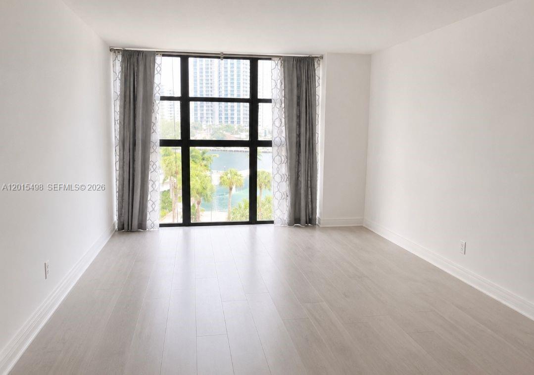 An empty room with light wood-look flooring and a large window overlooking a water view — 400 Leslie Dr # 508, Hallandale Beach FL 33009, HALLANDALE BEACH, FL