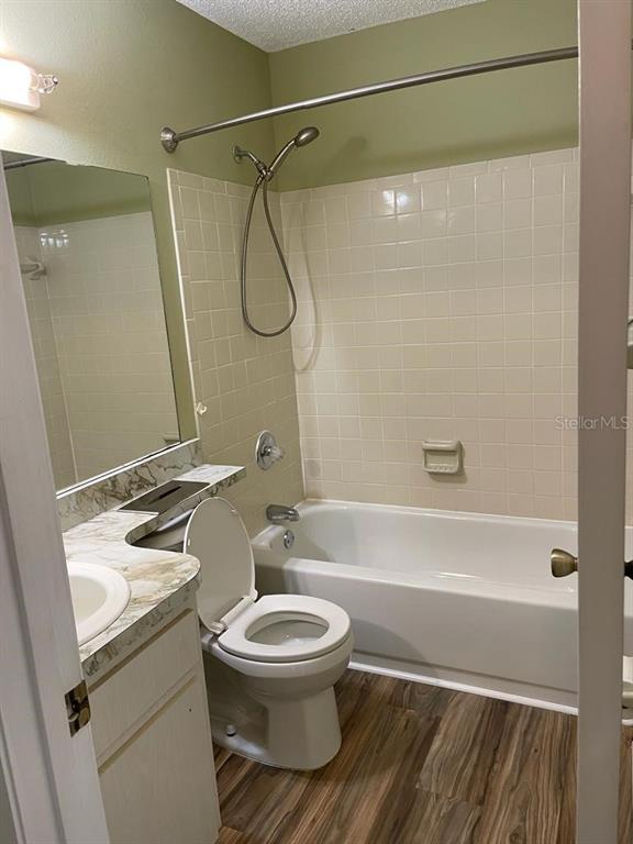 A bathroom features a vanity, a toilet, and a shower-tub combination with white wall tiles — 39132 COUNTY ROAD 54 UNIT 2084, ZEPHYRHILLS, FL