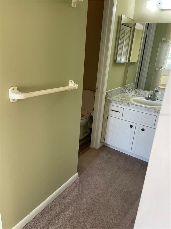 A bathroom features a vanity with a marble-look countertop, a toilet, and a towel bar — 39132 COUNTY ROAD 54 UNIT 2084, ZEPHYRHILLS, FL