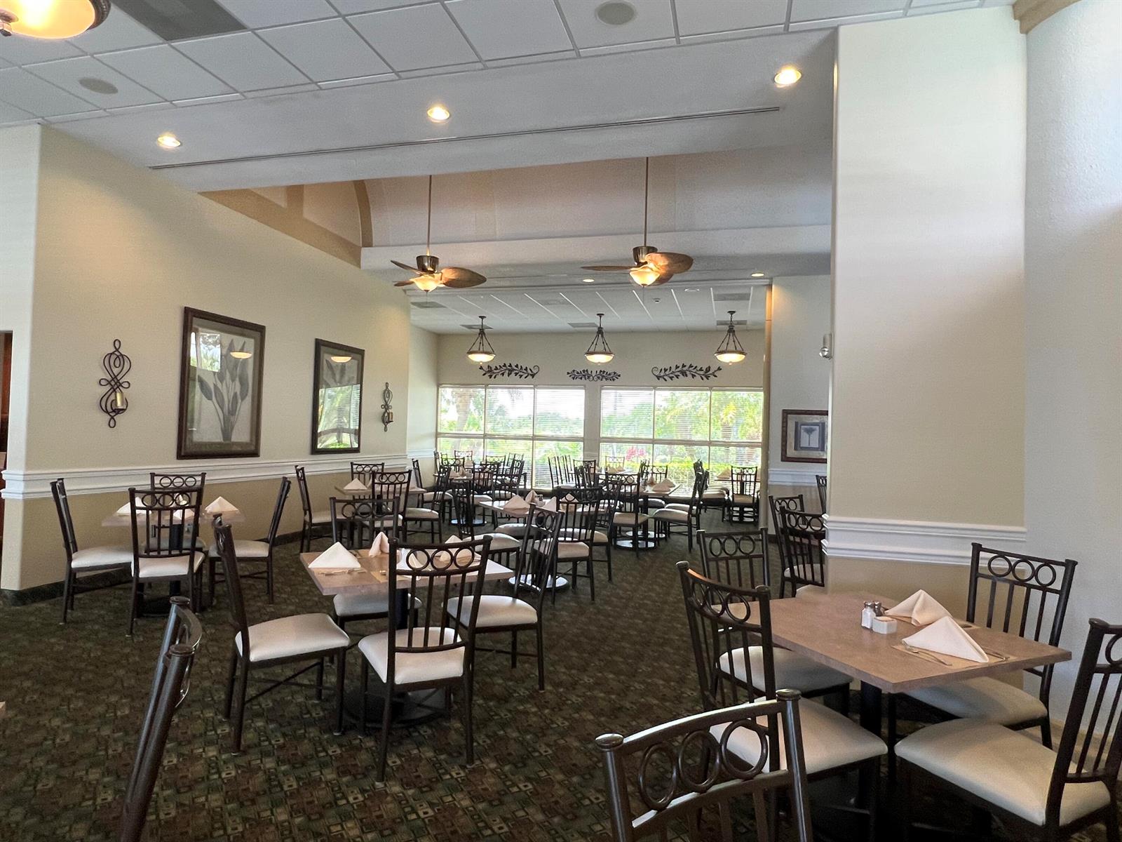 A dining room features multiple tables with chairs, ceiling fans, and large windows — 4310 Gator Trace Circle, Fort Pierce FL 34982, FORT PIERCE, FL