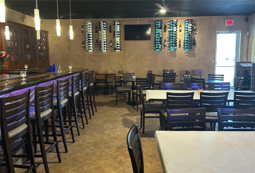 A restaurant interior features a bar with purple lighting, dining tables, and wall-mounted wine racks — 515 27TH STREET E UNIT 9, 10, 11, BRADENTON, FL