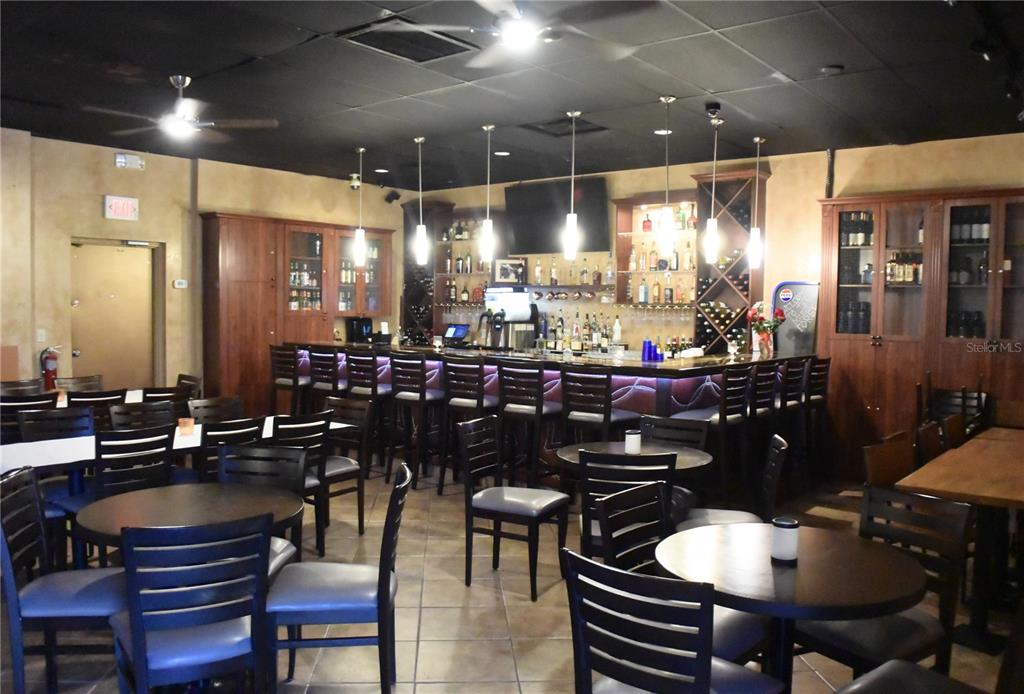 A restaurant interior features a long bar with stools, pendant lighting, and several dining tables — 515 27TH STREET E UNIT 9, 10, 11, BRADENTON, FL