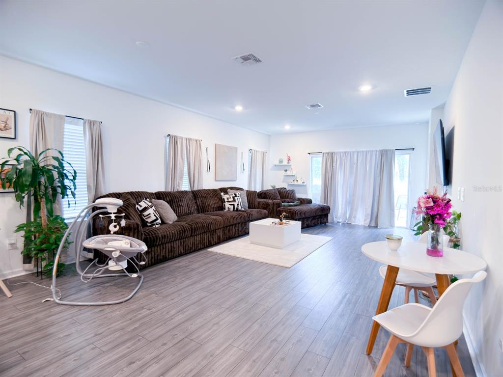 A living room features a large brown sectional sofa, light wood flooring, and a dining area — 4732 NW 11TH STREET, OCALA, FL