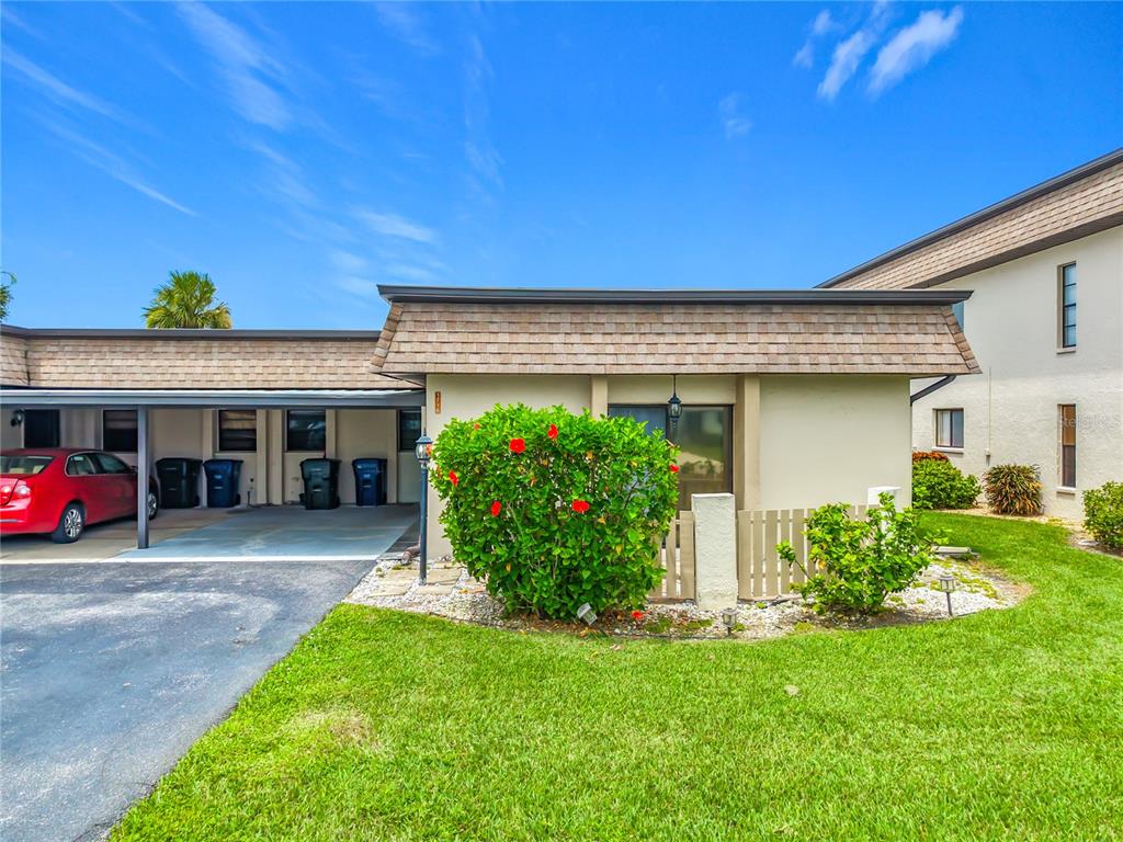 An exterior view of a single-story residential building with a central carport and driveway — 1716 LAKESIDE DRIVE UNIT 1714B, VENICE, FL