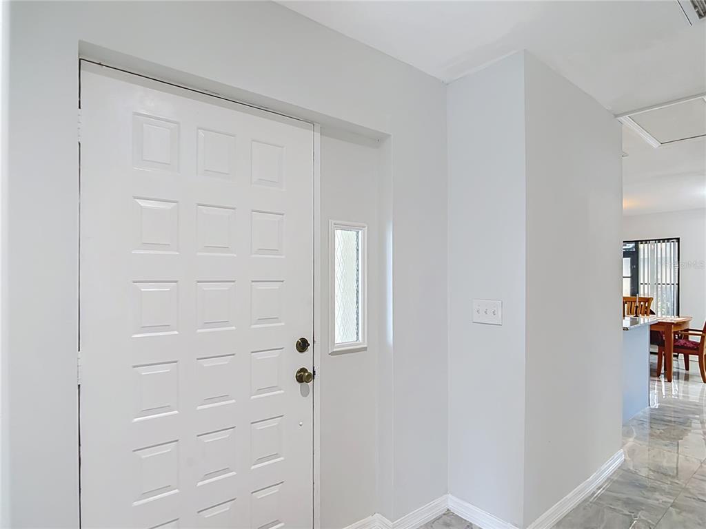 A white front door with a small side window opens into a light-colored entryway — 1716 LAKESIDE DRIVE UNIT 1714B, VENICE, FL