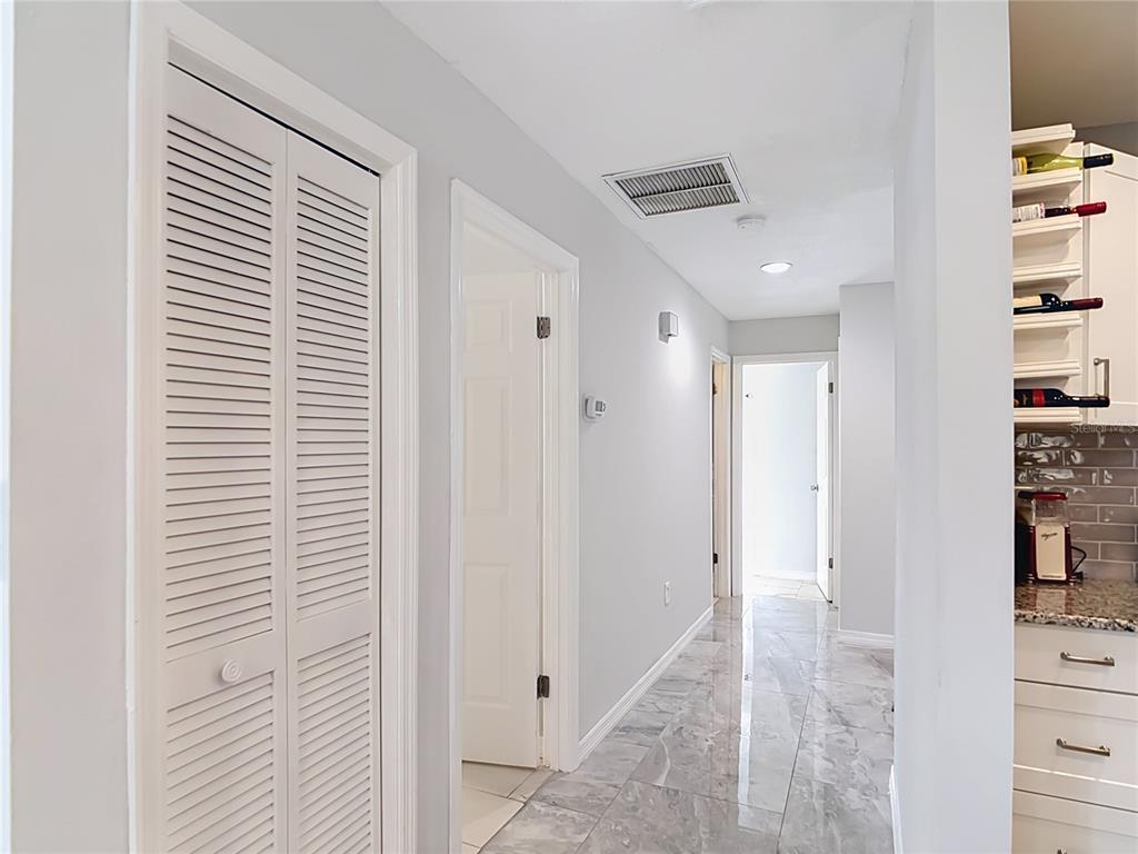 A hallway with light gray walls, marble-look tile flooring, and white louvered closet doors — 1716 LAKESIDE DRIVE UNIT 1714B, VENICE, FL