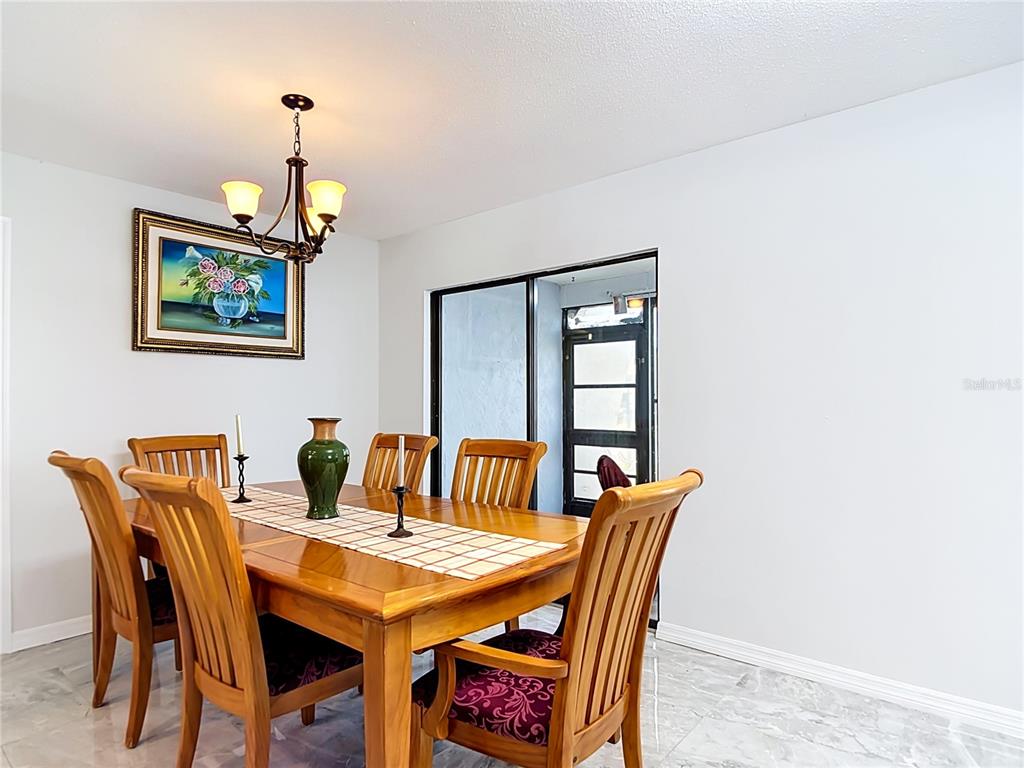 A dining room features a wooden table and chairs, a chandelier, and marble-style flooring — 1716 LAKESIDE DRIVE UNIT 1714B, VENICE, FL