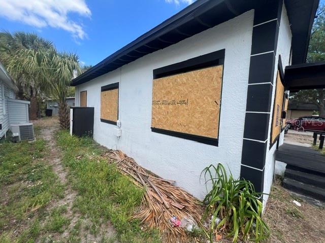 The exterior of a white house features black trim and windows boarded up with plywood — 1106 CARLTON STREET, CLEARWATER, FL