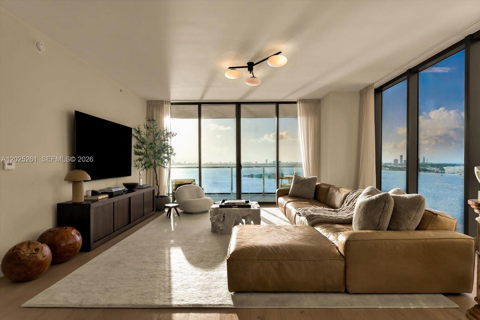A modern living room features a leather sectional, a large area rug, and floor-to-ceiling windows — 788 NE 23rd St # 1501, Miami FL 33137, MIAMI, FL