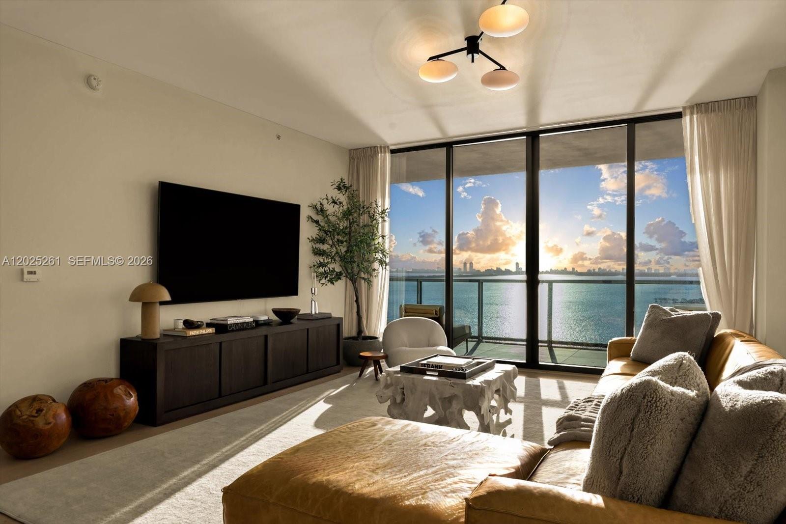 A living room features a dark media console, a leather sofa, and floor-to-ceiling windows — 788 NE 23rd St # 1501, Miami FL 33137, MIAMI, FL