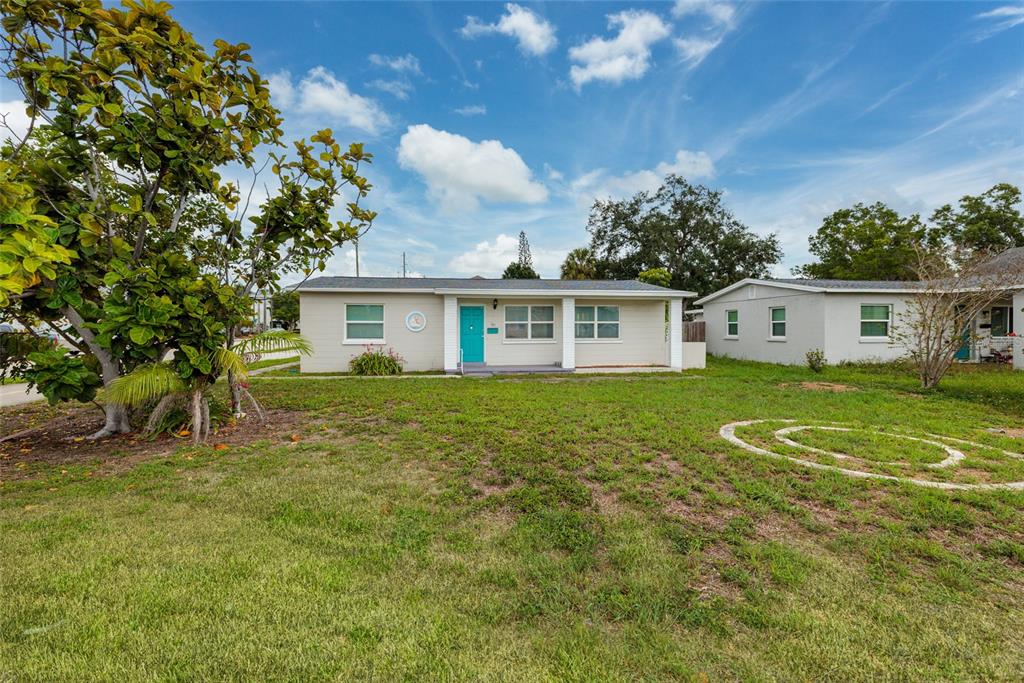 A single-story house with light siding and a bright blue front door sits on grass — 101 40TH AVENUE NE, ST PETERSBURG, FL