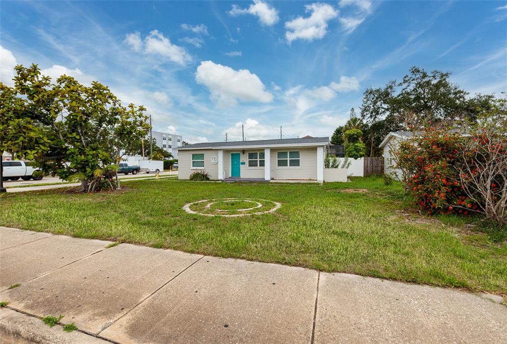 A single-story house with a light-colored exterior and a teal front door sits behind a lawn — 101 40TH AVENUE NE, ST PETERSBURG, FL
