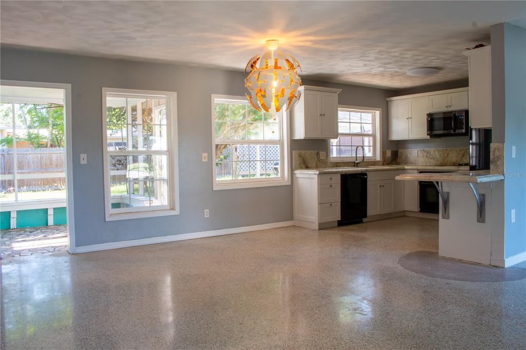 An open-concept kitchen and dining area features light gray walls, terrazzo floors, and white cabinetry — 2766 NAVEL DRIVE, CLEARWATER, FL