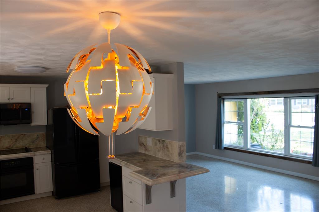 A modern spherical pendant light hangs in a kitchen with white cabinets and stone countertops — 2766 NAVEL DRIVE, CLEARWATER, FL