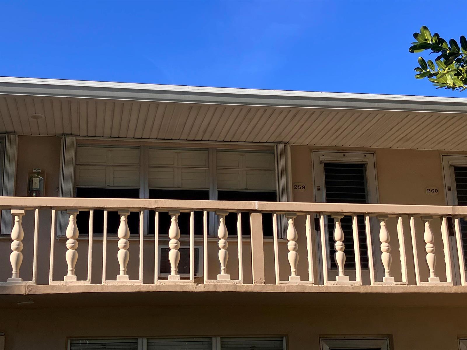 A beige building exterior features a balcony with balusters and numbered apartment doors — 259 Sheffield K # 259, West Palm Beach FL 33417, WEST PALM BEACH, FL