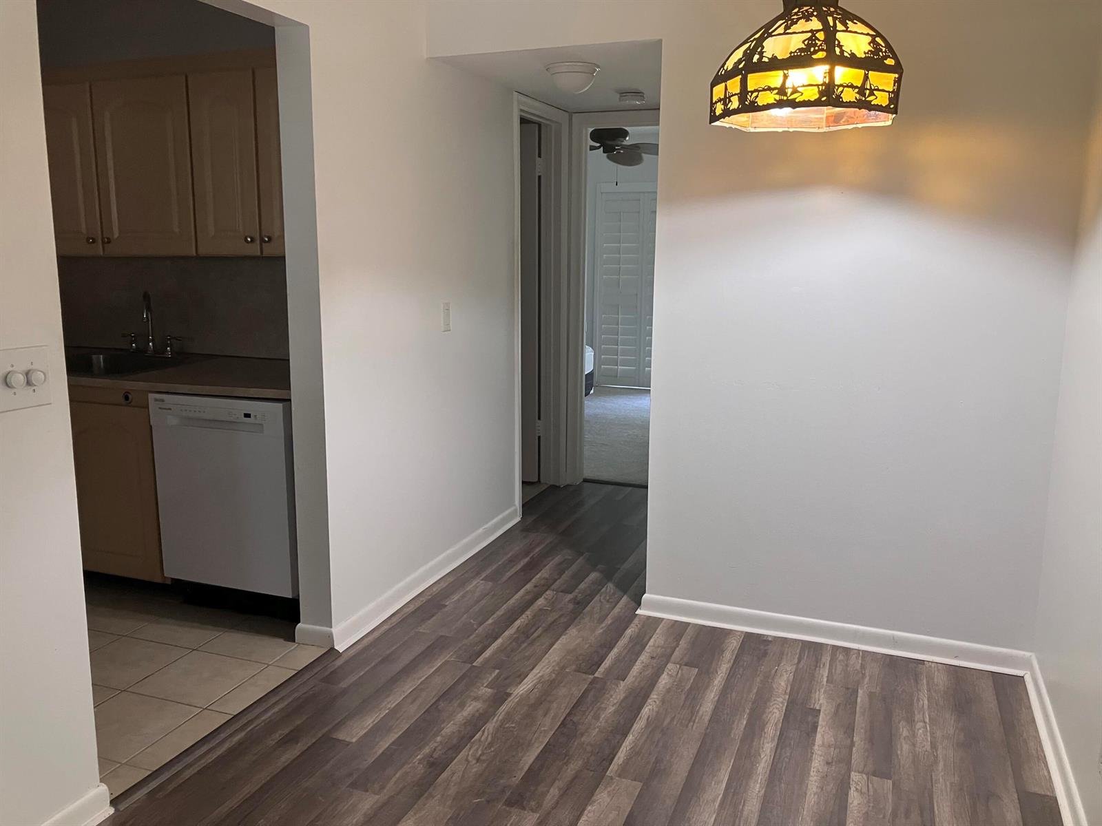 A view of a dining area with wood-look flooring, a pendant light, and an adjacent kitchen — 259 Sheffield K # 259, West Palm Beach FL 33417, WEST PALM BEACH, FL