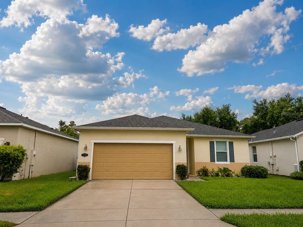 A single-story house with a tan stucco exterior, a two-car garage, and a concrete driveway — 2706 SPARTA DRIVE, NEW SMYRNA BEACH, FL