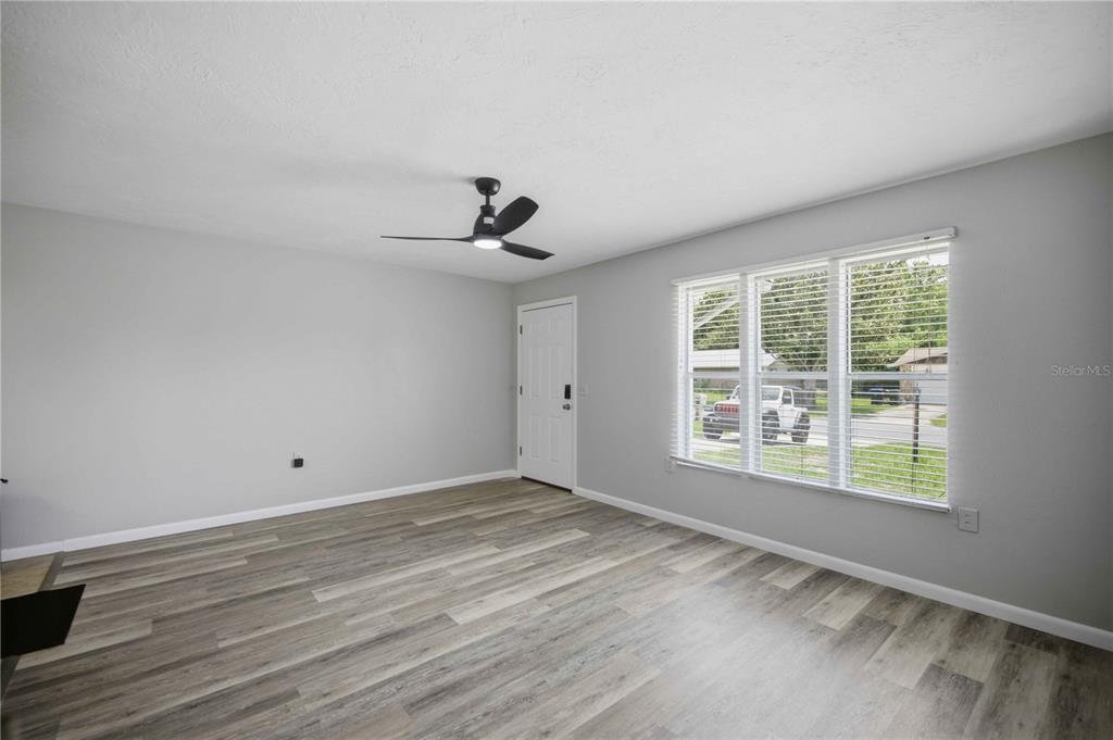 An empty room features gray walls, wood-look flooring, a ceiling fan, and a large window — 510 S ADAMS STREET, BEVERLY HILLS, FL
