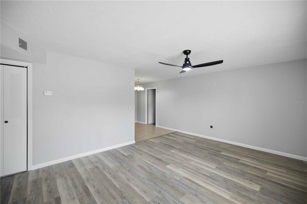 An empty living room features light gray walls, wood-look flooring, and a ceiling fan — 510 S ADAMS STREET, BEVERLY HILLS, FL
