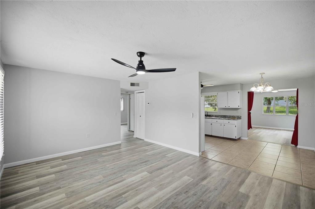 A living room with light gray walls, wood-look flooring, and an open view into the kitchen — 510 S ADAMS STREET, BEVERLY HILLS, FL