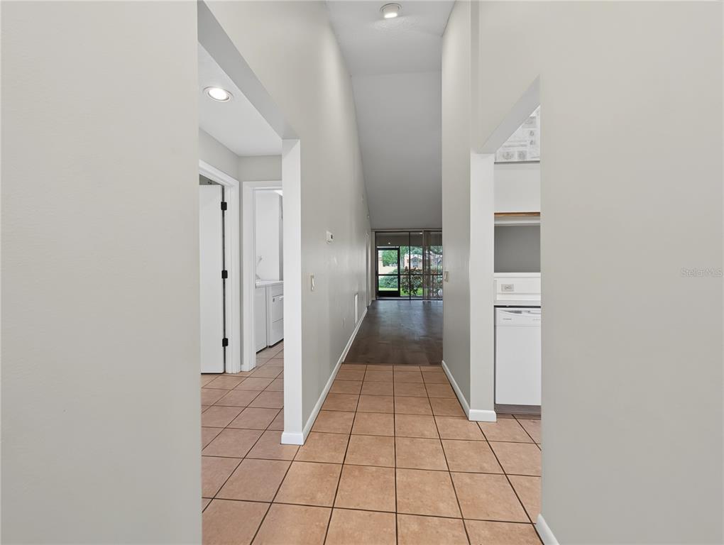A tiled hallway leads past a kitchen and laundry area toward a glass-enclosed patio — 4554 MORNINGSIDE UNIT 42, SARASOTA, FL