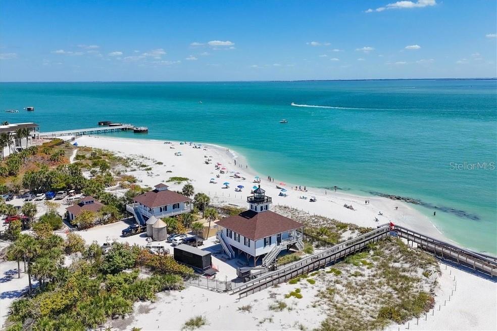 An aerial view shows a white sandy beach with a lighthouse and nearby coastal buildings — 870 GRANDE PASS WAY, BOCA GRANDE, FL