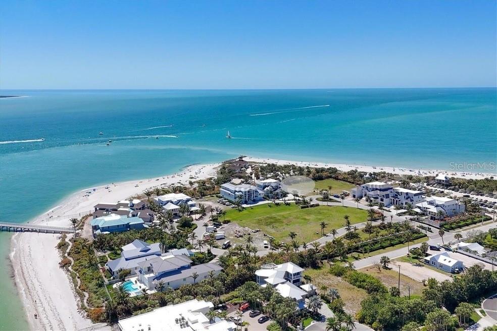 An aerial view shows a coastal neighborhood with houses, a large grassy lot, and a beach — 870 GRANDE PASS WAY, BOCA GRANDE, FL