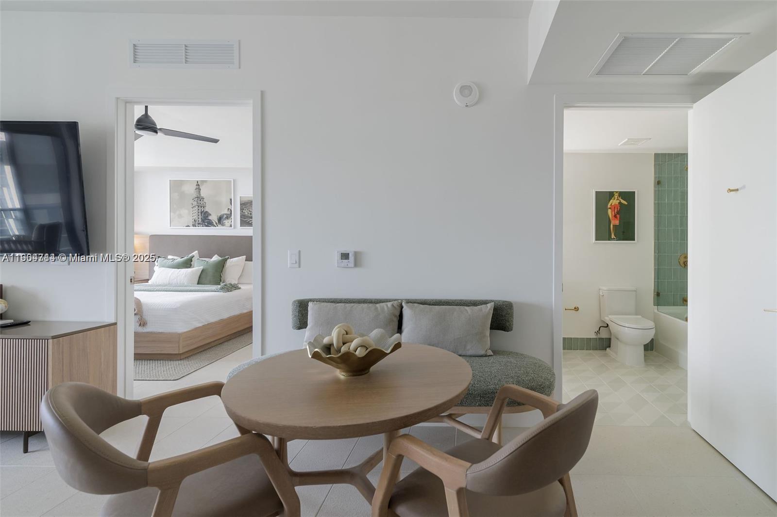 A dining area with a round table and chairs sits between a bedroom and bathroom — 159 NE 6th St # 2404, Miami FL 33132, MIAMI, FL