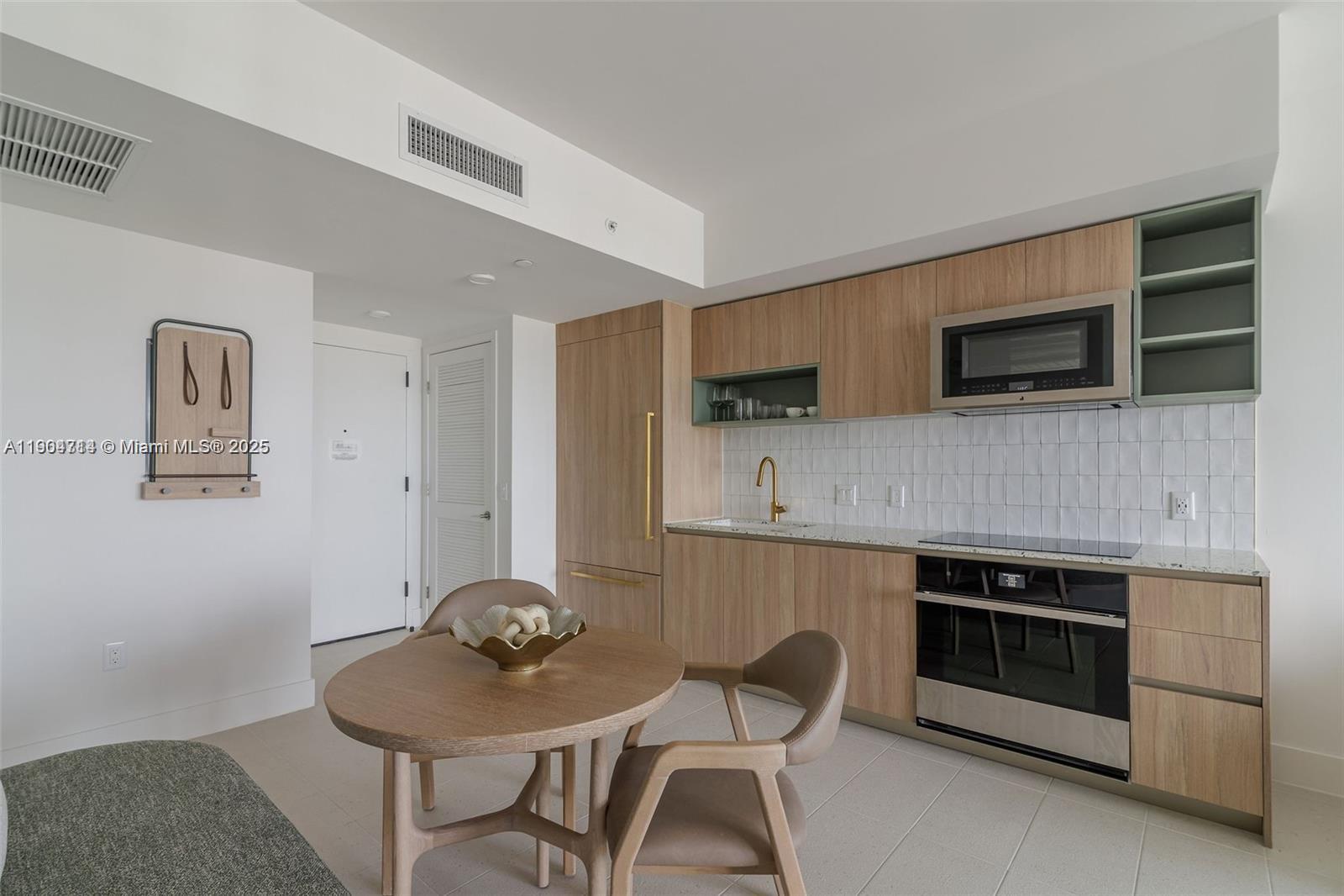 A modern kitchen features light wood cabinetry, a built-in microwave, and a small dining table — 159 NE 6th St # 2404, Miami FL 33132, MIAMI, FL