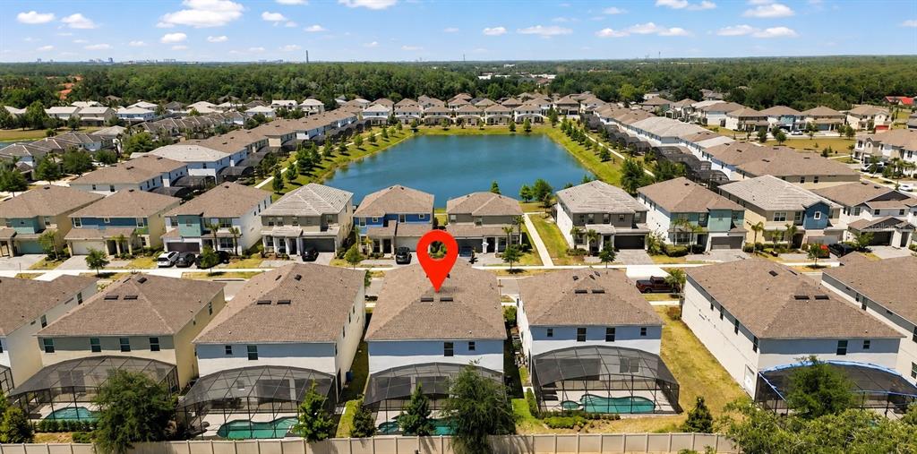 An aerial view shows a suburban neighborhood with houses surrounding a central lake — 294 MARCELLO BOULEVARD, KISSIMMEE, FL