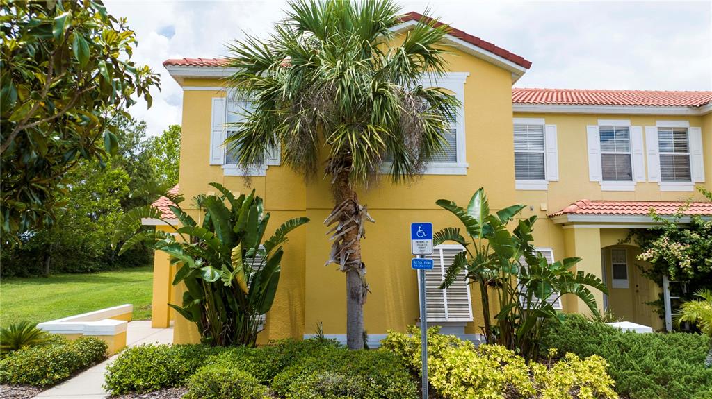 A two-story yellow stucco building with a palm tree and a handicap parking sign — 3022 WHITE ORCHID ROAD, KISSIMMEE, FL