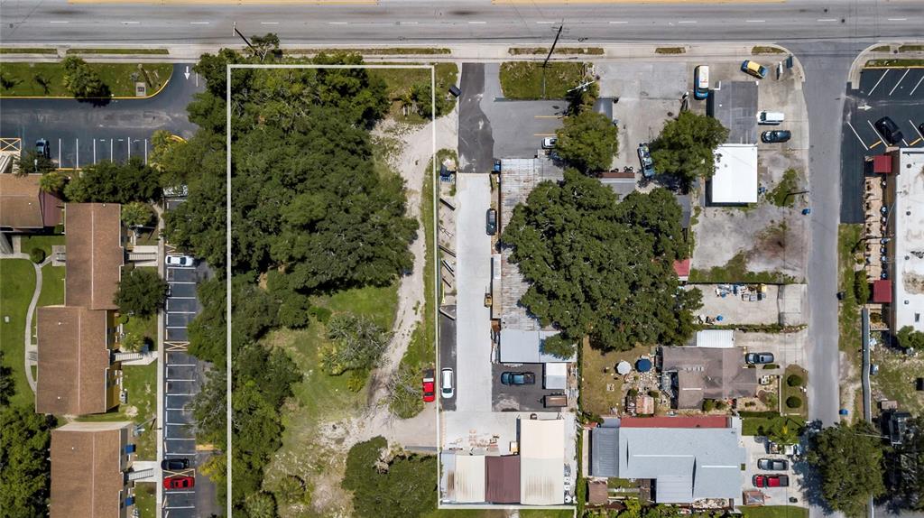 This aerial view shows a vacant lot adjacent to a commercial building and parking area — 6010 N ARMENIA AVENUE, TAMPA, FL