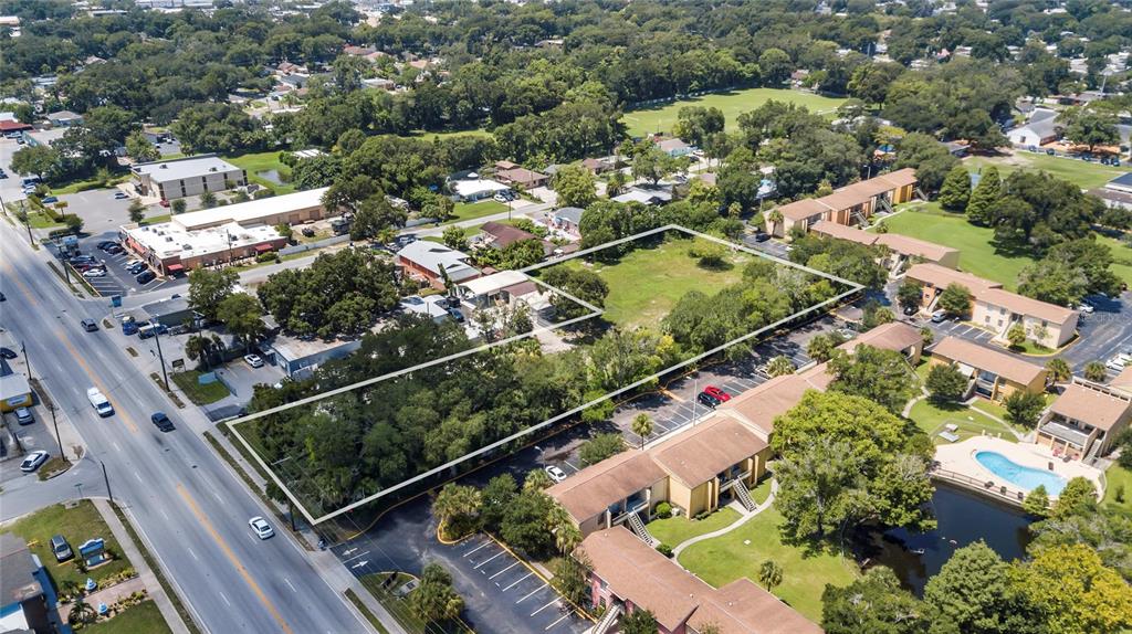 An aerial view shows a vacant, rectangular lot outlined in white near apartment buildings — 6010 N ARMENIA AVENUE, TAMPA, FL