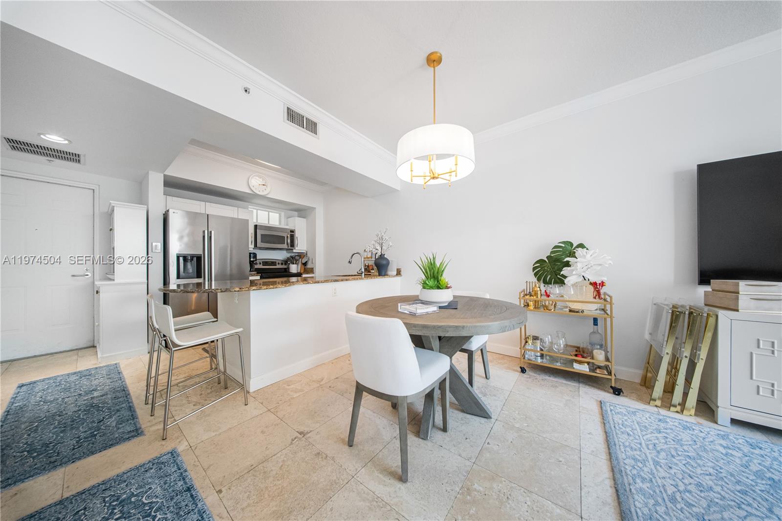 A kitchen with a breakfast bar and dining area features tile floors and white walls — 7290 SW 90th St # 308, Miami FL 33156, MIAMI, FL
